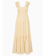A light yellow, ankle‑length dress with a soft floral pattern in pastel tones. The dress features a smocked bodice, a scoop neckline with ruffled edges, and short flutter sleeves. The skirt is tiered with subtle gathered seams, creating a flowing, airy silhouette.