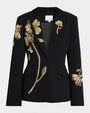 Black single-button blazer with gold floral embroidery across the front and sleeve, featuring peaked lapels and flap pockets.