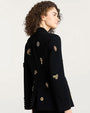 Back view of a black tailored blazer decorated with ornate embroidered and jeweled embellishments, including dragonflies, flowers, and other decorative motifs in gold, red, and metallic tones.