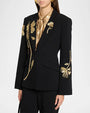 Black tailored blazer with gold floral embroidery on the front and sleeve, styled over a metallic gold tie-neck blouse.
