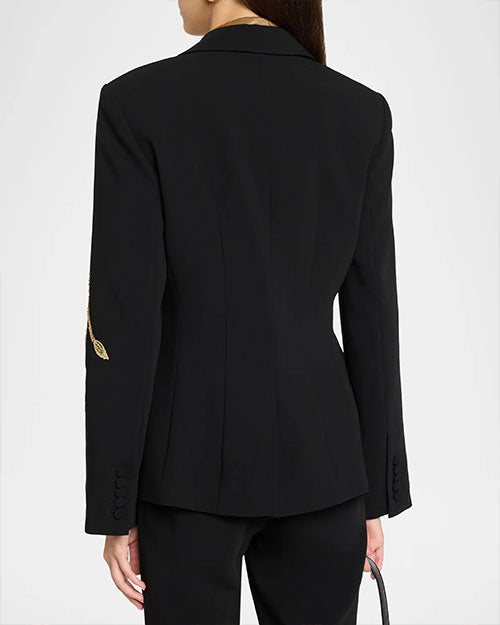 Back view of a fitted black tailored blazer with a single gold embroidered leaf detail on the sleeve and a structured silhouette.