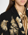 Black tailored blazer with gold floral embroidery on the front and sleeve, styled over a metallic gold tie-neck blouse.