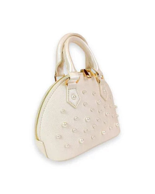 Side view of a small ivory dome-shaped handbag with dual top handles, gold-tone hardware, and decorative pearl studs on the front.
