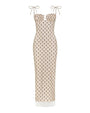 A sleeveless, cream-colored maxi dress with thin shoulder tie straps and a fitted silhouette. The dress features a small black floral print pattern throughout and a subtle cut-out detail at the bust. The hemline reaches the ankles.