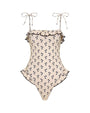 One-piece swimsuit in a cream color with a small black floral print pattern. The design features thin shoulder tie straps, ruffled trim along the neckline and hips, and a matching headscarf accessory.