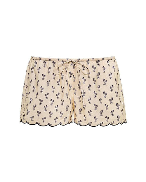 Cream-colored shorts with a small black floral print, scalloped hem with black trim, and a drawstring tie at the waist.