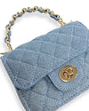 Small light blue denim handbag with a quilted diamond pattern, gold-tone twist-lock closure, and a short handle made of interwoven blue material and gold chain links, shown in a close-up angled view.