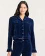 “Front view of a person wearing a dark blue velvet jacket with button closure, flap chest pockets, and ruffled cuffs, paired with matching velvet pants.”