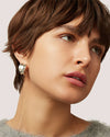 Close-up of a person wearing a chunky, polished silver hoop earring with a bold, rounded design.