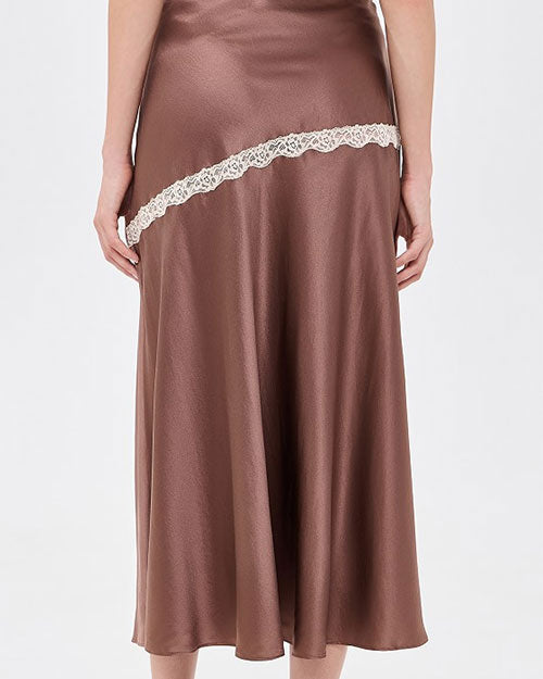 Close-up of a mauve satin midi skirt with contrast ivory lace trim in an asymmetrical diagonal panel, creating a flowing, slip-inspired silhouette.