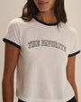 Close-up view of a white short-sleeve ringer T-shirt with navy contrast trim at the crew neckline and sleeve cuffs. The graphic T-shirt features the text “THE FAVORITE” printed in an arched collegiate-style font across the chest. Shown against a light neutral background.