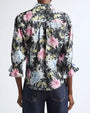 Black button-front blouse with a painterly floral print in pink, white, and green, featuring a pointed collar and three-quarter sleeves with ruffled cuffs.