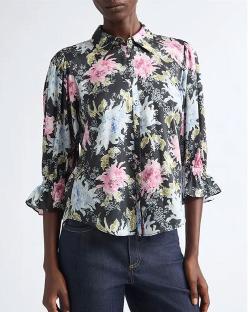 Black button-front blouse with a painterly floral print in pink, white, and green, featuring a pointed collar and three-quarter sleeves with ruffled cuffs.