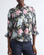 Black button-front blouse with a painterly floral print in pink, white, and green, featuring a pointed collar and three-quarter sleeves with ruffled cuffs.