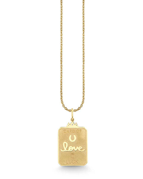 Gold necklace with a rectangular pendant engraved with “CARD OF” at the top, a horseshoe symbol, the word “love” in cursive, and “LUCK” at the bottom.