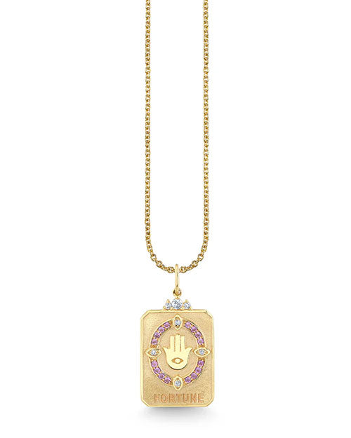 Gold necklace with a rectangular pendant engraved with a hand featuring an eye in the center, surrounded by pink gemstones and small diamond-like stones, with the word “FORTUNE” at the bottom.