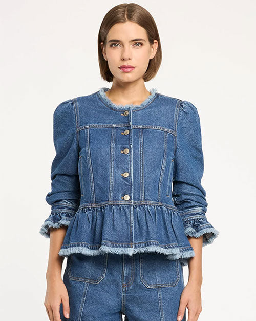 Front studio view of a cropped denim peplum jacket featuring a round neckline, front button closure, structured seams, long sleeves with gathered ruffle cuffs, and frayed trim along the hem and collar, paired with matching denim bottoms, photographed against a light background.