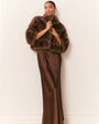 Front view of an outfit featuring a cropped brown faux fur jacket with a plush, textured finish, styled over a floor-length satin slip dress in a matching brown tone.
