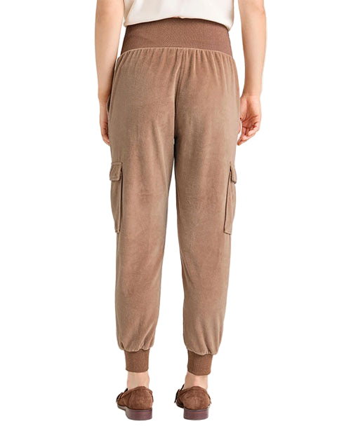 Back view of light brown velvet jogger-style pants featuring a wide ribbed waistband, ribbed cuffs, and side cargo pockets, paired with brown loafers.