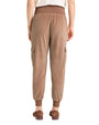 Back view of light brown velvet jogger-style pants featuring a wide ribbed waistband, ribbed cuffs, and side cargo pockets, paired with brown loafers.