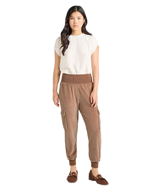Front view of an outfit featuring a white short-sleeve top paired with light brown velvet jogger-style pants that have a wide ribbed waistband, ribbed cuffs, and side cargo pockets, styled with brown loafers.
