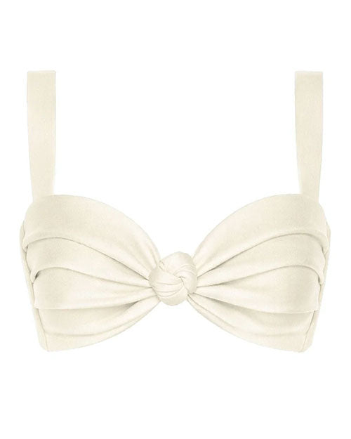 A cream-colored bikini top with thick shoulder straps and softly ruched cups. The fabric is gathered toward the center, where a small knotted detail creates a twist effect. The overall design is structured, minimal, and symmetrical, with smooth, matte material and clean stitching.
