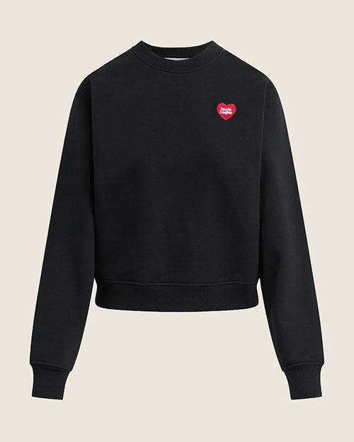 A black crewneck sweatshirt with long sleeves and ribbed cuffs and hem. The sweatshirt features a small red heart graphic with white text on the upper left chest.