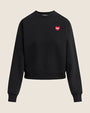 A black crewneck sweatshirt with long sleeves and ribbed cuffs and hem. The sweatshirt features a small red heart graphic with white text on the upper left chest.