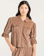 Front view of a light brown velvet zip-up jacket featuring a pointed collar, two button-flap chest pockets, and elbow-length puff sleeves with gathered cuffs.