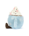 Plush toy shaped like a light blue cup of hot chocolate with embroidered snowflakes, a handle, and white plush whipped cream topped with pink and brown accents resembling marshmallows and chocolate sprinkles. Two brown legs extend from the bottom of the cup.