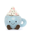 Plush toy shaped like a blue mug with a handle on the right side, featuring embroidered snowflakes and a smiling face. The top is filled with white plush material resembling whipped cream, topped with pink and brown accents resembling marshmallows and chocolate chips.