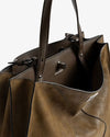 Close-up view of an brown leather tote bag showing its spacious interior, structured design, dual top handles, and metal clasp detail. The inner lining appears textured with a subtle brand logo visible.