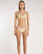 Person standing against a neutral backdrop, wearing a yellow floral bikini. 