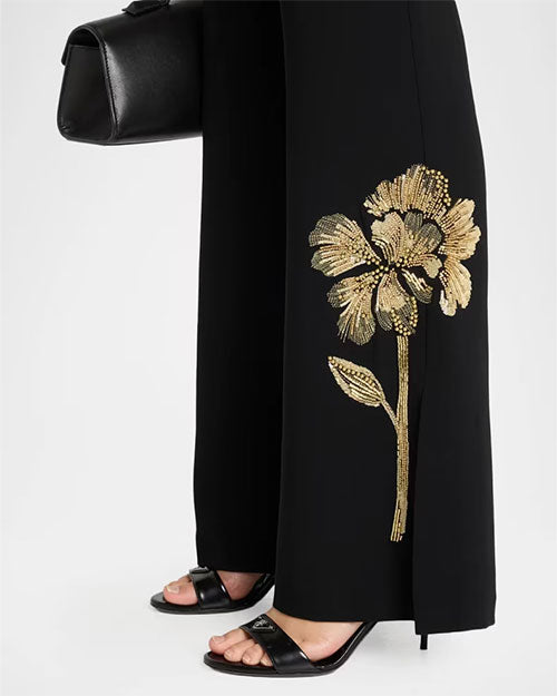 Close up detail of black flared pants with gold floral beaded embroidery at the hem.