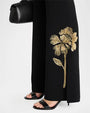 Close up detail of black flared pants with gold floral beaded embroidery at the hem.