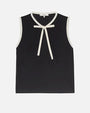 Sleeveless black top with white trim along the neckline and armholes, featuring a white bow detail at the front near the collar.