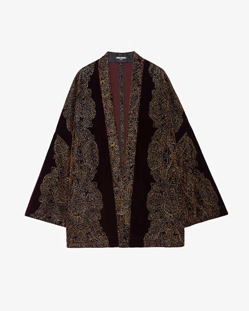 A long, open-front kimono-style jacket made of deep burgundy velvet fabric. The garment features intricate, ornate paisley embroidery in metallic gold and black thread along the front edges, sleeves, and hemline. The design creates a luxurious and elegant appearance with a rich texture and detailed craftsmanship.