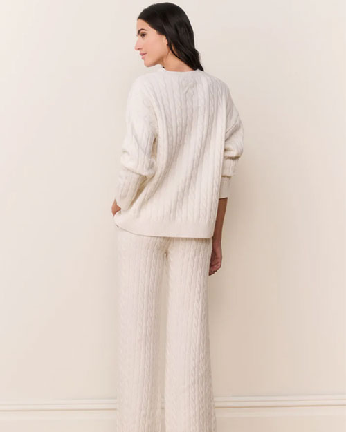 Back view of a cream-colored cable-knit sweater paired with matching wide-leg knit pants. The sweater has a relaxed fit with long sleeves and a ribbed hem, while the pants feature a similar textured pattern for a coordinated look.