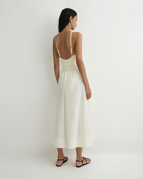 Rear view of a person modeling a sleeveless cream camisole with thin straps and matching wide-leg pants featuring a drawstring waist, paired with black flat sandals against a plain light background.