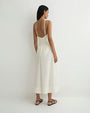 Rear view of a person modeling a sleeveless cream camisole with thin straps and matching wide-leg pants featuring a drawstring waist, paired with black flat sandals against a plain light background.