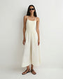 Person modeling a sleeveless cream camisole with thin straps and matching wide-leg pants featuring a drawstring waist, paired with black flat sandals and sunglasses against a plain light background.