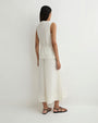 Rear view of a person modeling an ivory sleeveless wrap-style top with a side tie and matching wide-leg cropped pants against a plain light background.