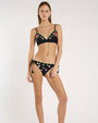 Image of a person wearing a scalloped black bikini top embroidered with green leaves and pink and purple flowers. 