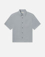 Product image of a light blue short-sleeve button-down shirt displayed flat against a light background, featuring a pointed collar, a full button front with tonal buttons, a single chest pocket, and a subtle textured fabric. The shirt has a clean, relaxed silhouette with straight hem.