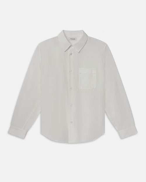 Product image of a lightweight off-white long-sleeve button-down shirt displayed flat against a light background, featuring a pointed collar, full button front with tonal buttons, and a single chest pocket. The shirt has a smooth, minimal design with a gently curved hem and a relaxed, tailored silhouette.