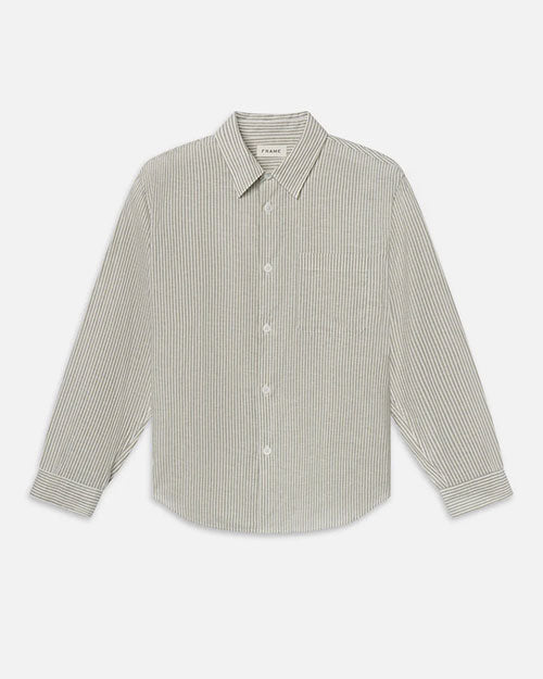 Product image of a long-sleeve button-down shirt displayed flat against a light background, featuring fine vertical stripes in soft neutral tones. The shirt has a pointed collar, full button front, single chest pocket, and a gently curved hem, with a clean, tailored silhouette.