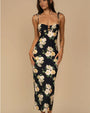 Person wearing a fitted, sleeveless black dress with thin tie straps and a large floral print featuring white and light yellow flowers with green leaves.