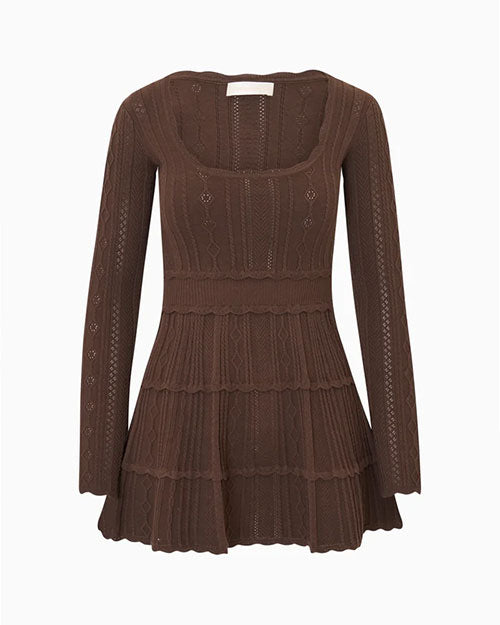 Brown knit mini dress with long sleeves and a scoop neckline, displayed against a light gray background. The dress features an intricate pointelle knit pattern throughout, a fitted bodice, a defined waist with scalloped trim, and a three-tiered flared skirt with matching scalloped edges.