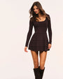 Full-length view of a dark chocolate-brown knit mini dress with long sleeves and a square neckline. The dress features a fitted ribbed bodice, a defined waist, and a tiered skirt with subtle ruffled trim between each tier. The model is wearing knee-high dark brown boots and standing against a light neutral background.