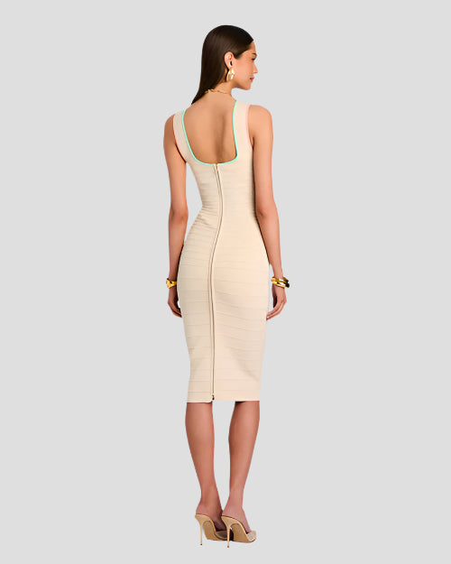 A backside view of a brunette model wearing a below the knee dress, with a round low-neck back with a blue outline and a zipper down the middle, which also appear down the middle on a pink stripe. She is also wearing large gold earrings, gold heels, and gold bracelets. The background is plain white.